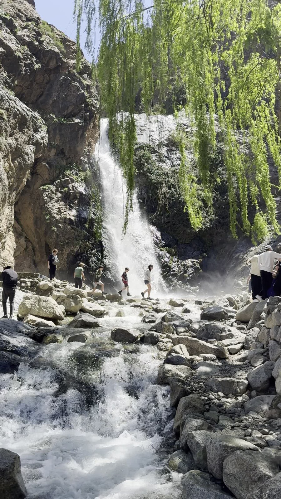 Waterfall and hikers crossing rocks in the Atlas mountains near Imlil